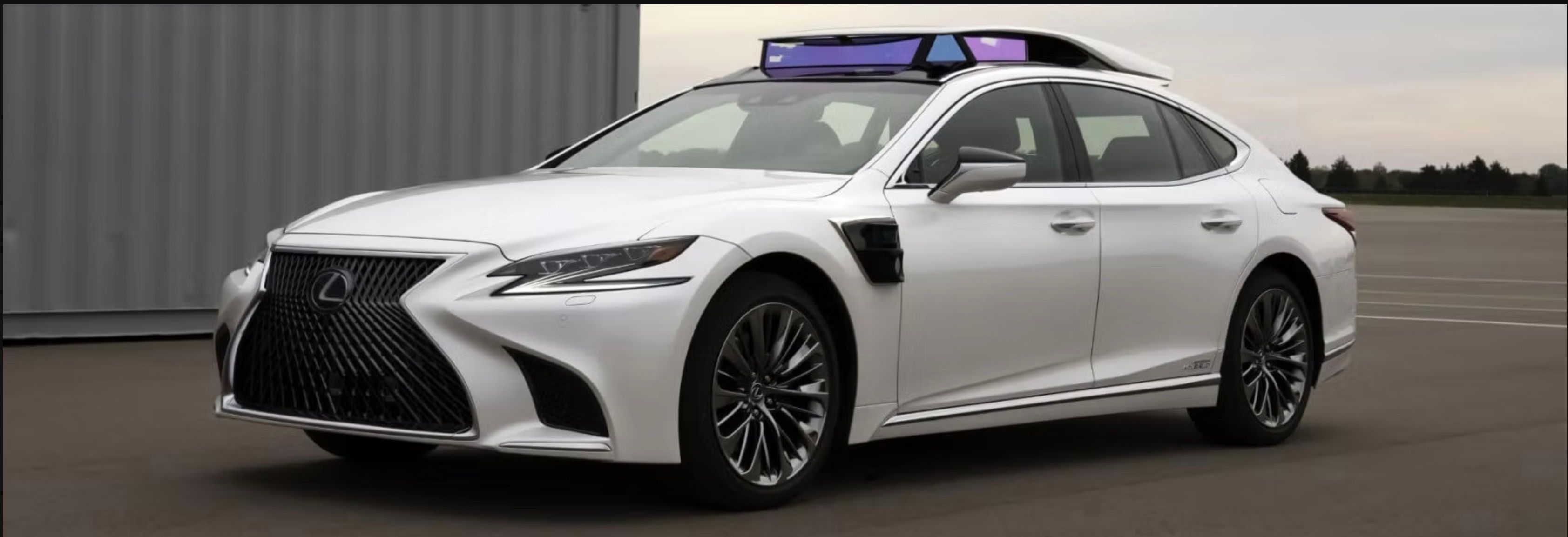 A Toyota Research Institute autonomous research vehicle, a white Lexus sedan with a roof-mounted sensor array.